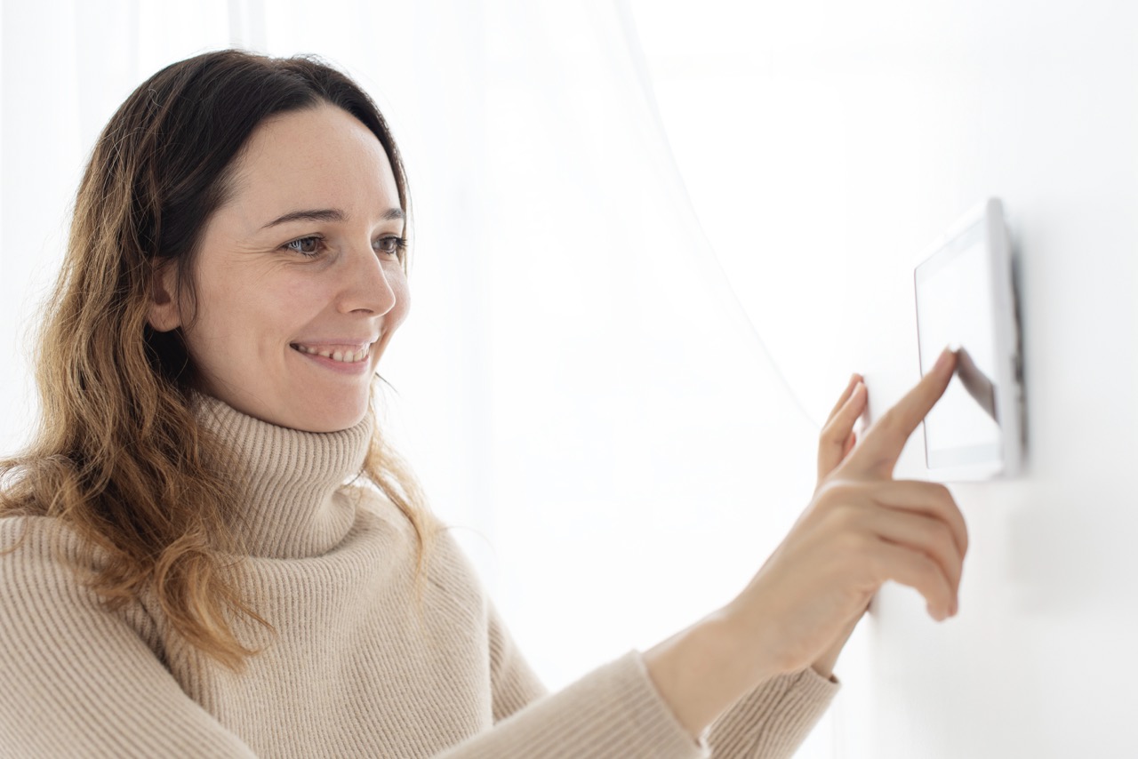 Woman pressing on smart home automation panel monitor